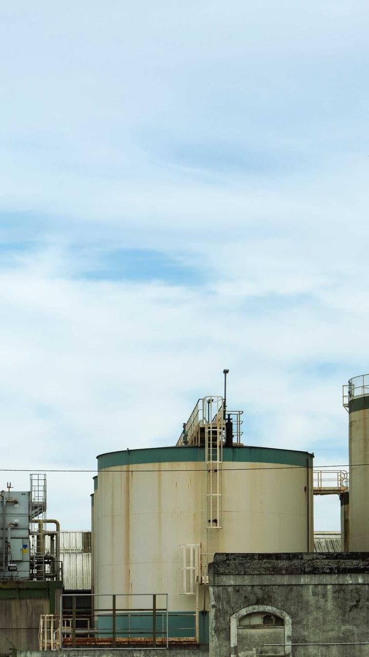 Silos and pipework of a small industrial plant under a blue sky