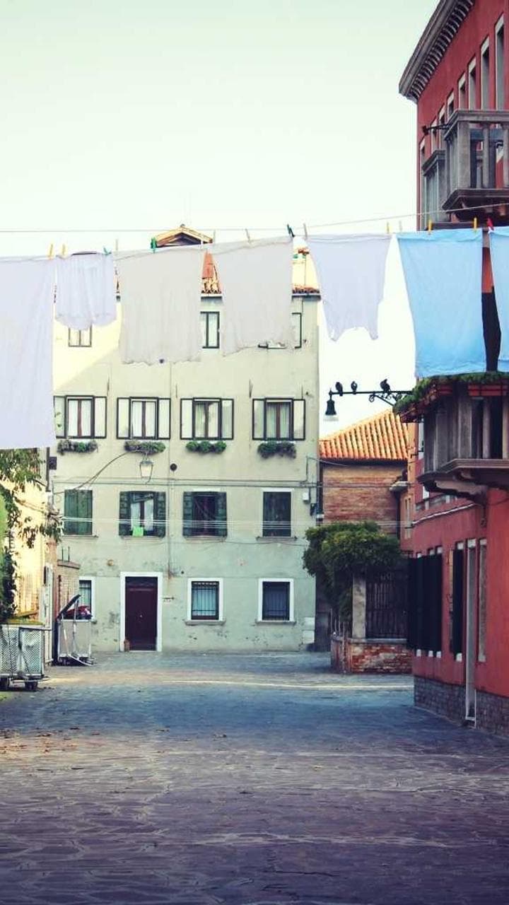 A narrow street of painted houses with laundry lines between them